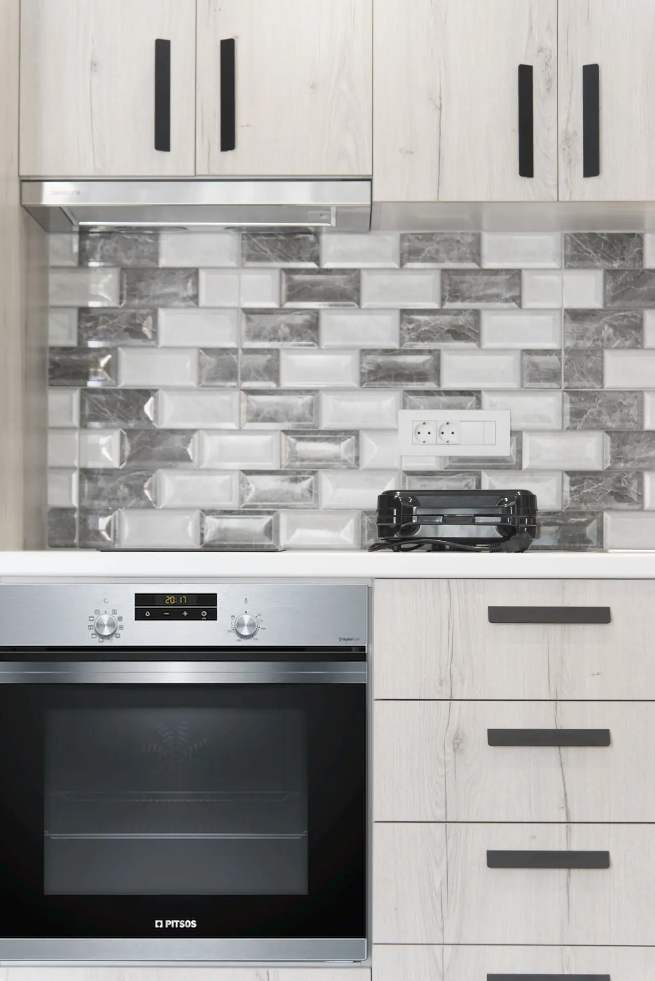 Kitchen with oven, drawers and a grey brick splashback